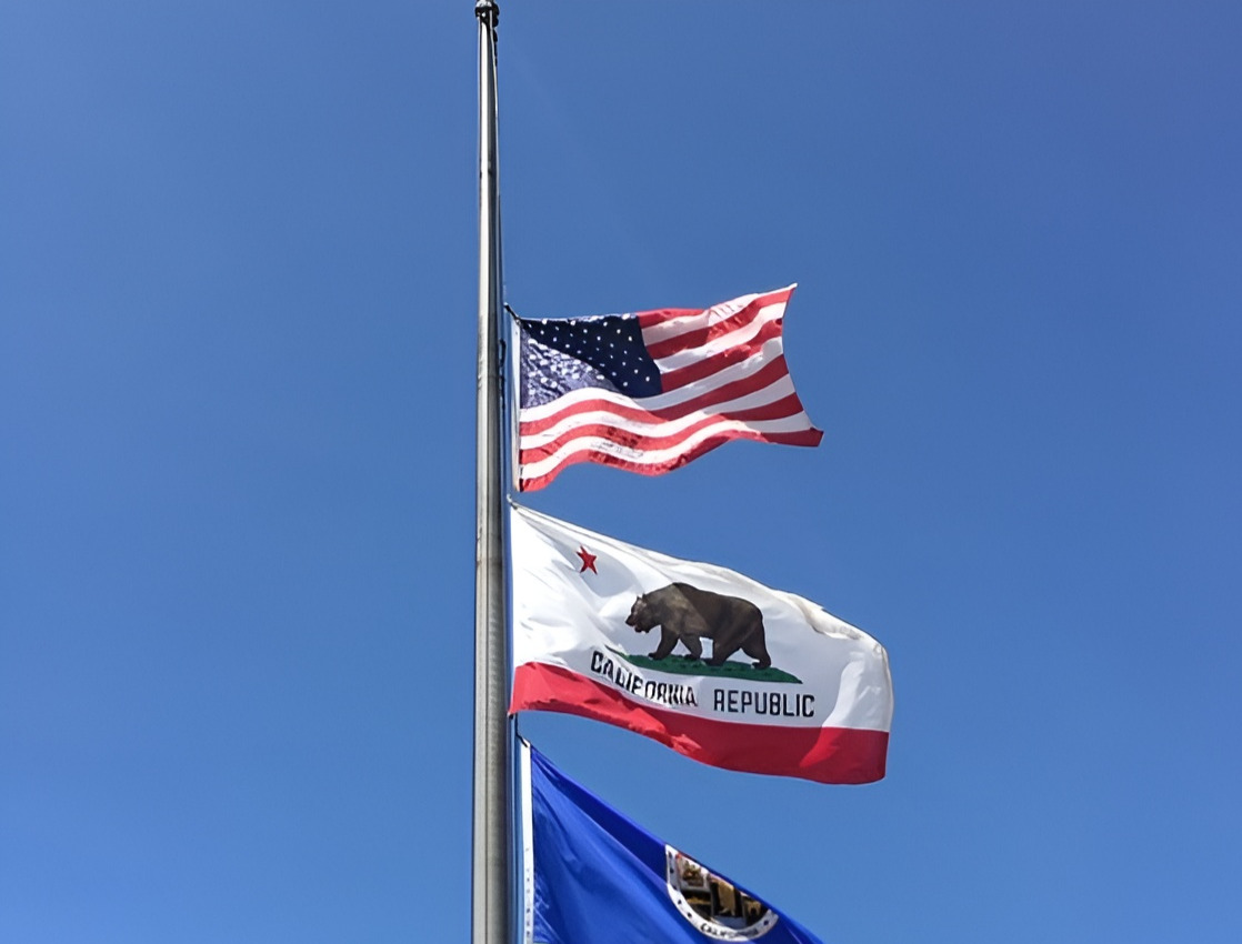 Three flags fly at half-mast, the United States flag, California flag and flag of Los Angeles
