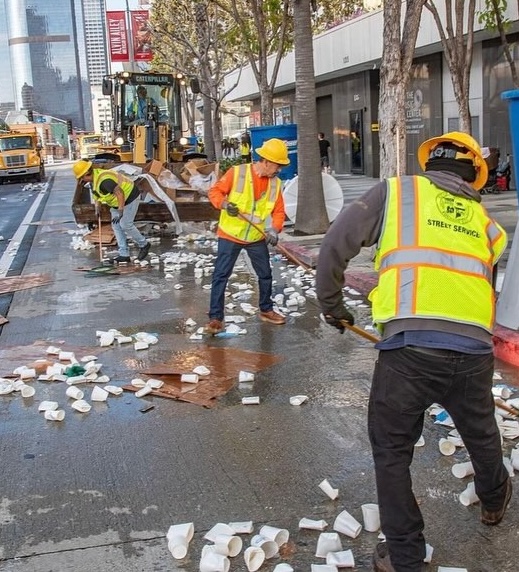 City workers clean trash out of the street after a community event.